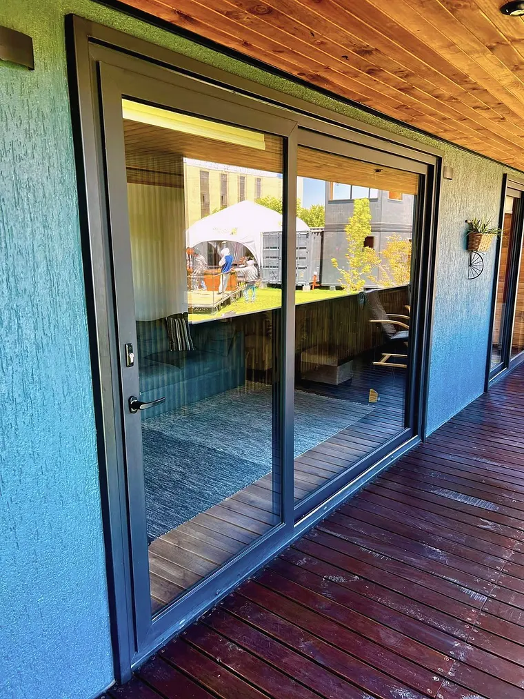 Puerta corredera de termopanel en acceso a terraza de casa modular