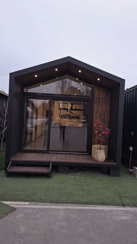 Fachada de casa modular negra con ventanal fijo y puerta corredera de termopanel