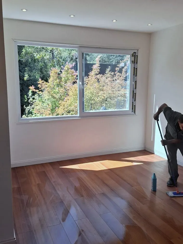 Ventana corredera de PVC blanco recién instalada en vivienda, con operario terminando la obra
