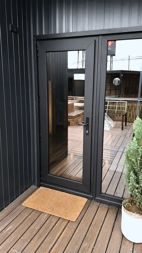 Puerta abatible de PVC negro con vidrio termopanel sobre deck de madera